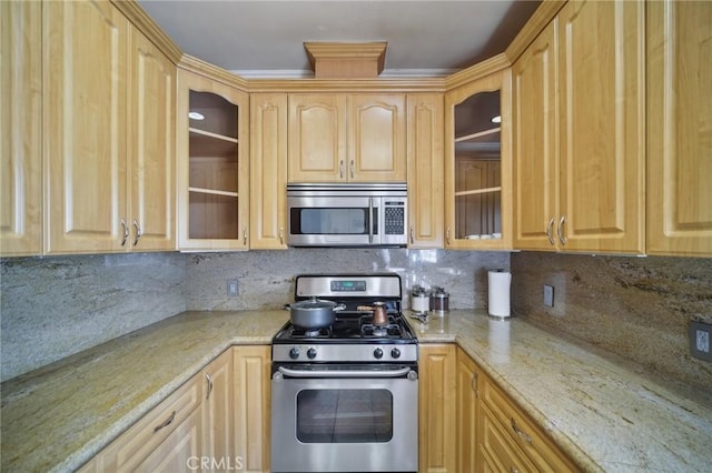 kitchen with stainless steel appliances, tasteful backsplash, light stone countertops, and light brown cabinetry