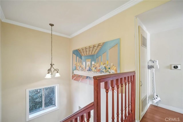 corridor featuring an inviting chandelier, ornamental molding, and hardwood / wood-style floors