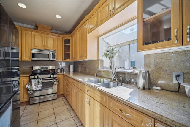 kitchen featuring sink, light tile patterned floors, appliances with stainless steel finishes, light stone counters, and tasteful backsplash