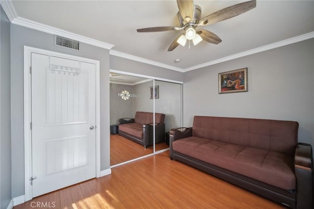 living room featuring wood-type flooring, ornamental molding, and ceiling fan