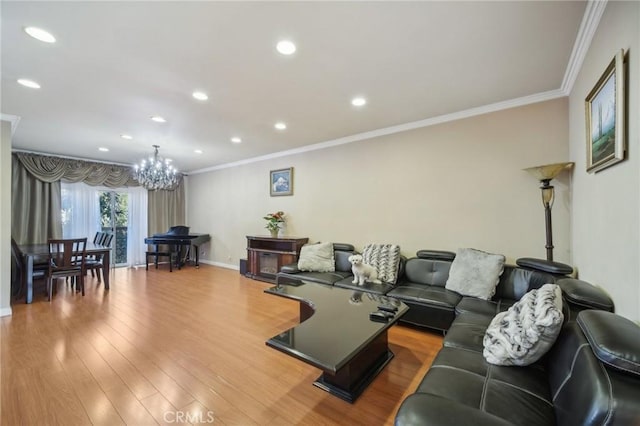 living room with a notable chandelier, light hardwood / wood-style flooring, and ornamental molding