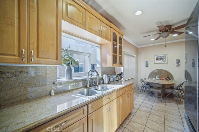 kitchen featuring sink, decorative backsplash, light tile patterned floors, light stone counters, and crown molding