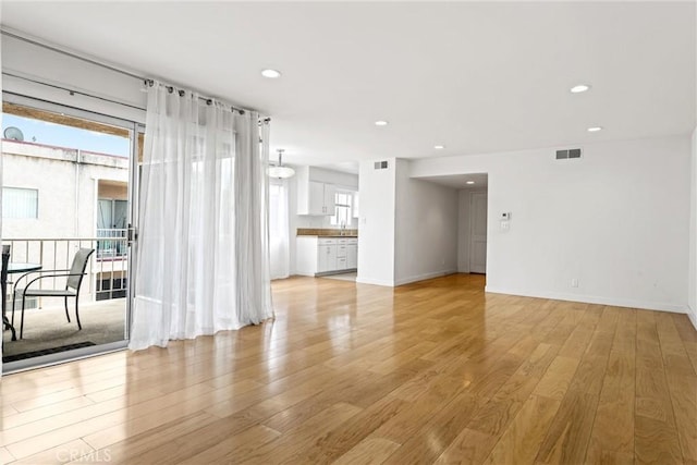 spare room featuring a healthy amount of sunlight, sink, and light hardwood / wood-style flooring