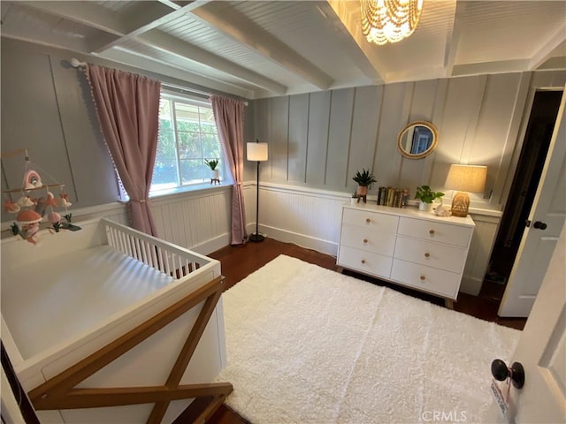 bedroom featuring dark wood-type flooring, beam ceiling, and a notable chandelier