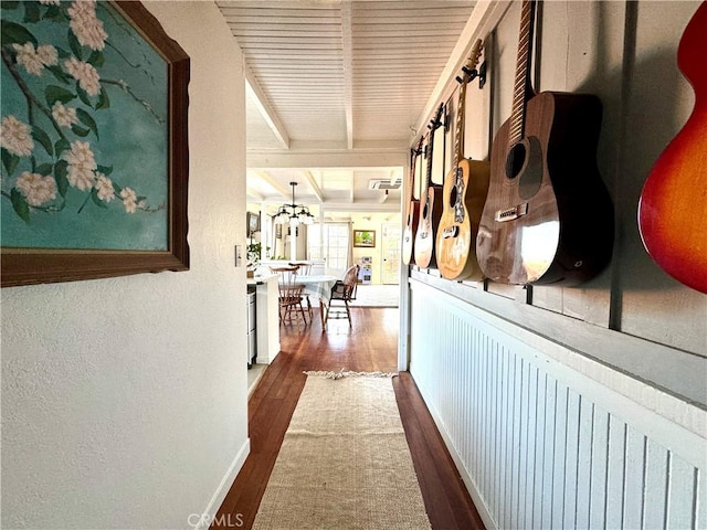 corridor featuring dark hardwood / wood-style floors, a chandelier, and beam ceiling