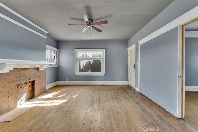 unfurnished living room with ceiling fan, a fireplace, and light hardwood / wood-style flooring