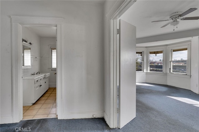 corridor featuring sink and light colored carpet