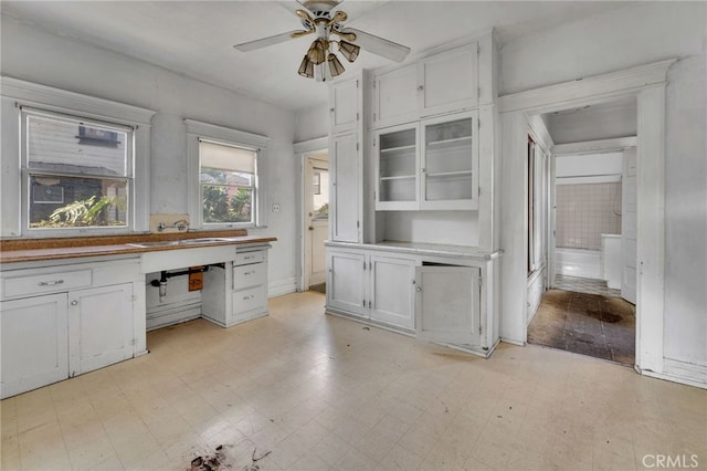 kitchen with ceiling fan, built in desk, sink, and white cabinets