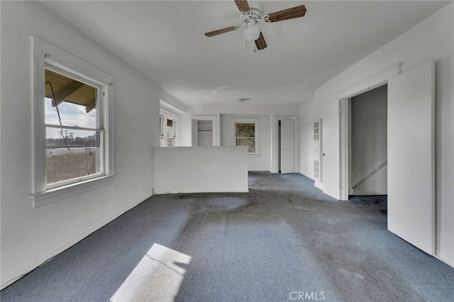 unfurnished room with ceiling fan and dark colored carpet