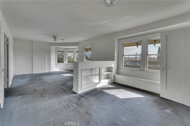 unfurnished living room with ceiling fan and dark colored carpet