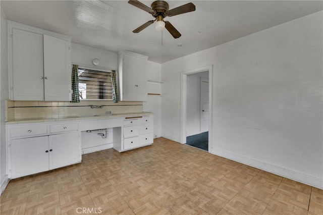 interior space featuring backsplash, light parquet flooring, white cabinets, and ceiling fan