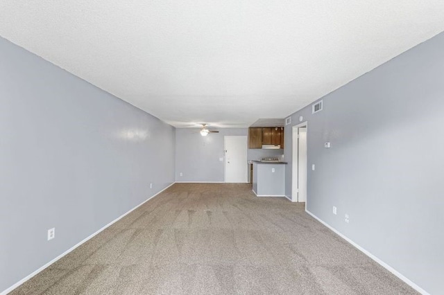 unfurnished living room featuring ceiling fan, carpet, and a textured ceiling