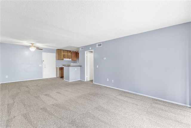 unfurnished living room featuring light carpet, a textured ceiling, and ceiling fan