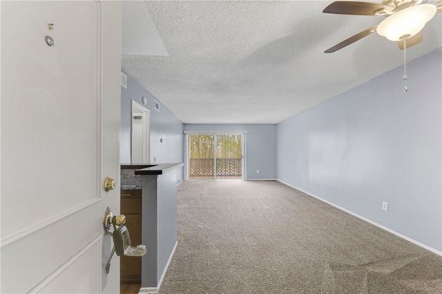 unfurnished living room with ceiling fan, carpet, and a textured ceiling