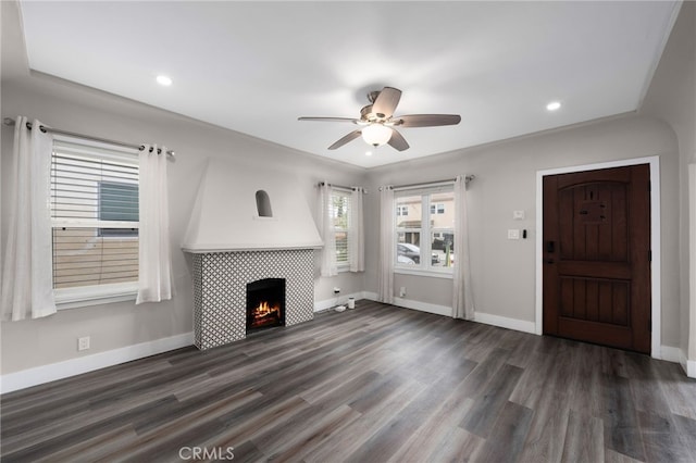 unfurnished living room with ceiling fan, dark hardwood / wood-style flooring, and a tile fireplace