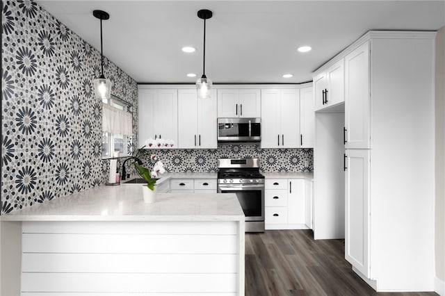 kitchen with decorative light fixtures, kitchen peninsula, white cabinets, and appliances with stainless steel finishes