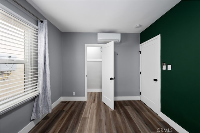 unfurnished bedroom featuring dark hardwood / wood-style flooring and an AC wall unit