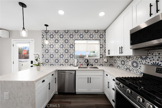 kitchen with sink, white cabinetry, stainless steel appliances, decorative light fixtures, and kitchen peninsula