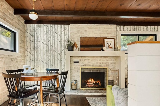 living area featuring beamed ceiling, plenty of natural light, a brick fireplace, and wooden ceiling