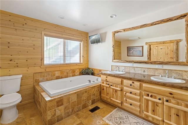 bathroom with tiled tub, vanity, and toilet