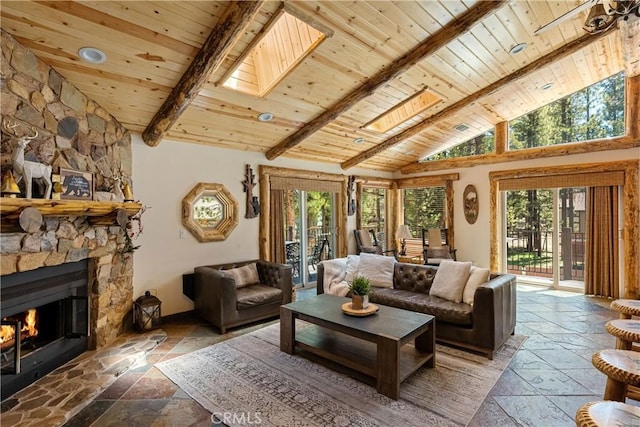 living room with beamed ceiling, a stone fireplace, wood ceiling, and a skylight