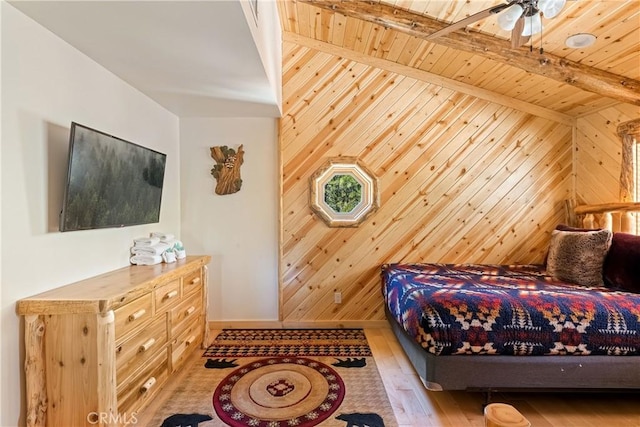 bedroom with wood ceiling, beam ceiling, light hardwood / wood-style flooring, and wood walls