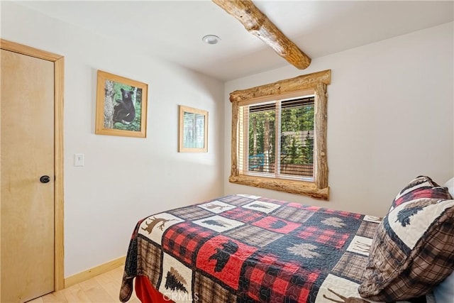 bedroom with light hardwood / wood-style flooring and beamed ceiling