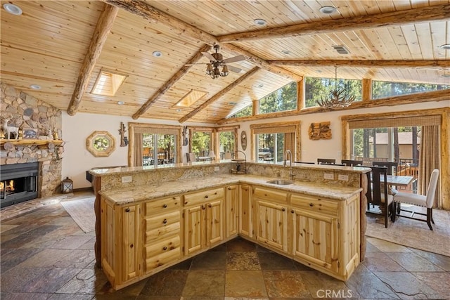 kitchen with a stone fireplace, sink, light stone counters, wooden ceiling, and beam ceiling