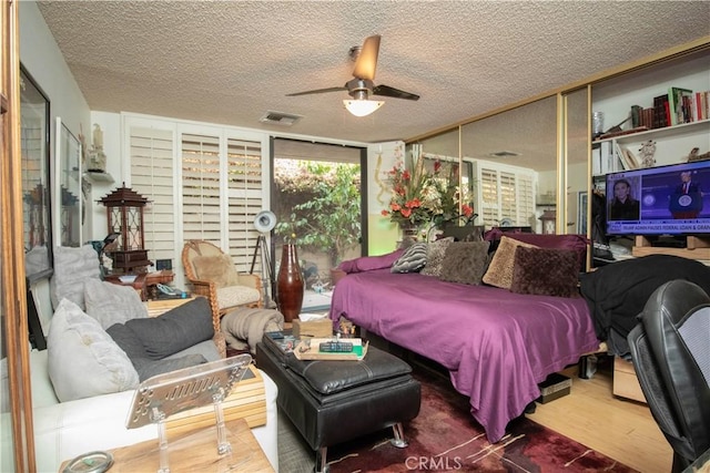 bedroom with hardwood / wood-style floors, a textured ceiling, and ceiling fan