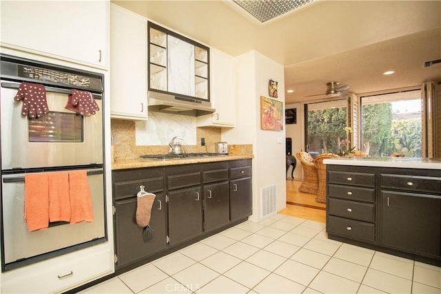 kitchen with backsplash, light tile patterned flooring, double oven, and white cabinets