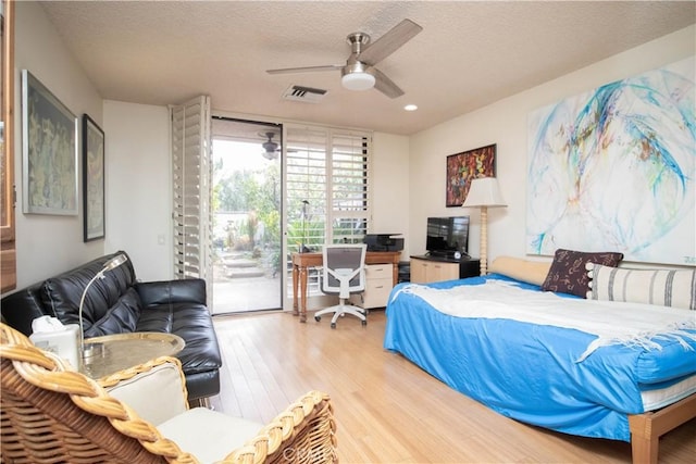 bedroom featuring expansive windows, access to outside, ceiling fan, a textured ceiling, and light hardwood / wood-style flooring