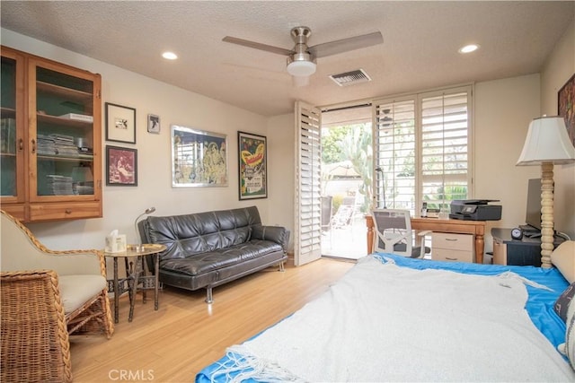 bedroom with a wall of windows, a textured ceiling, ceiling fan, access to exterior, and light hardwood / wood-style floors