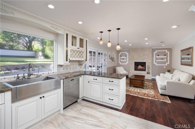 kitchen with sink, white cabinetry, hanging light fixtures, stainless steel dishwasher, and dark stone counters