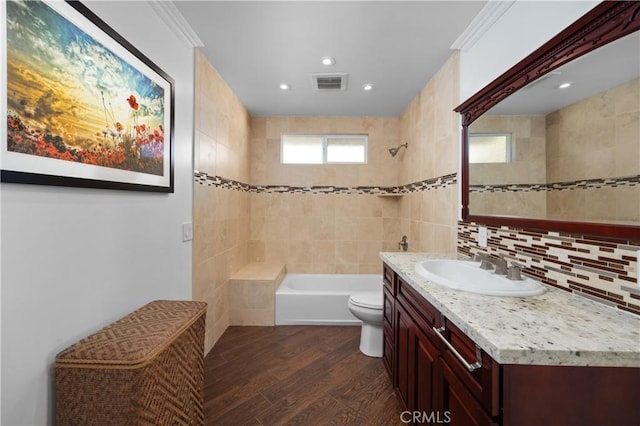 full bathroom featuring hardwood / wood-style floors, decorative backsplash, tiled shower / bath combo, vanity, and toilet