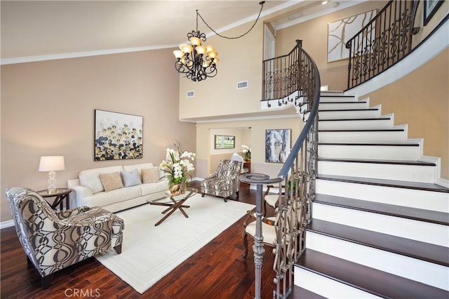 living room with a towering ceiling, ornamental molding, dark hardwood / wood-style floors, and a notable chandelier