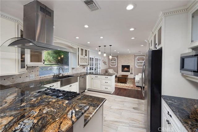 kitchen with pendant lighting, stainless steel appliances, island range hood, white cabinets, and kitchen peninsula