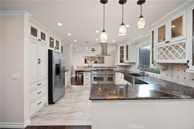 kitchen featuring pendant lighting, sink, stainless steel appliances, island range hood, and kitchen peninsula