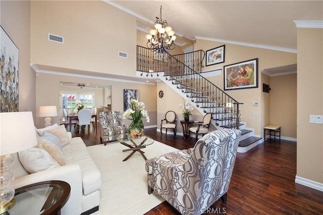 living room with a high ceiling, crown molding, dark wood-type flooring, and a chandelier