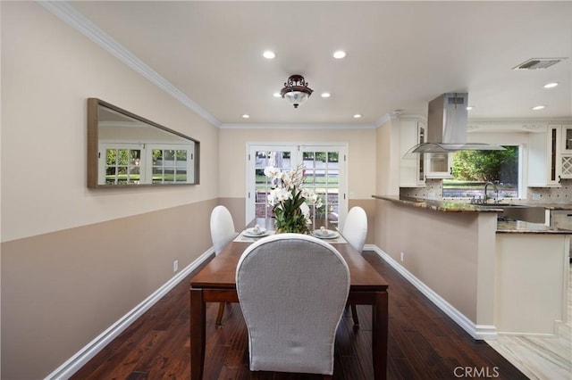 dining room with sink, crown molding, dark wood-type flooring, and a healthy amount of sunlight