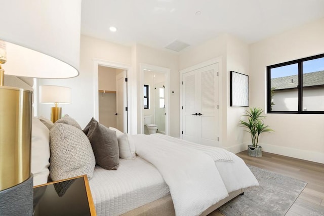 bedroom featuring ensuite bath, light hardwood / wood-style floors, and a closet