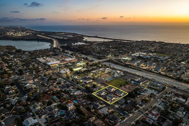 aerial view at dusk featuring a water view