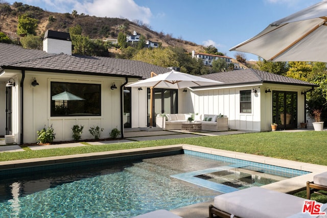 back of house with outdoor lounge area, a mountain view, and a lawn