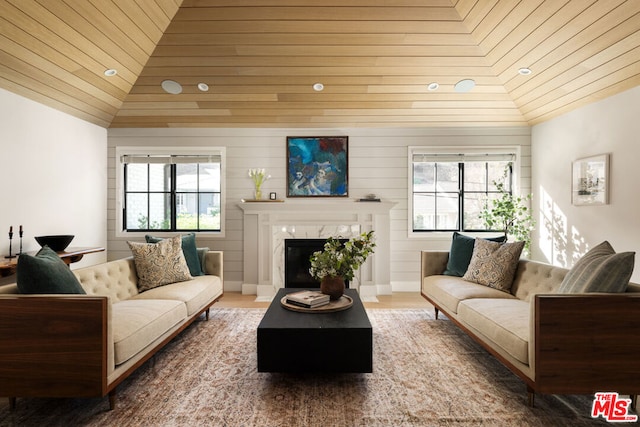 living room with a high end fireplace, vaulted ceiling, and a healthy amount of sunlight