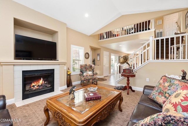 living room featuring lofted ceiling and a tiled fireplace