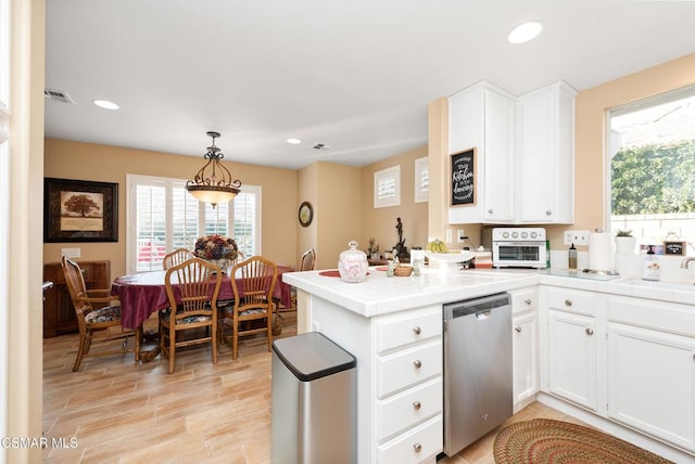 kitchen with dishwasher, white cabinets, hanging light fixtures, tile counters, and kitchen peninsula