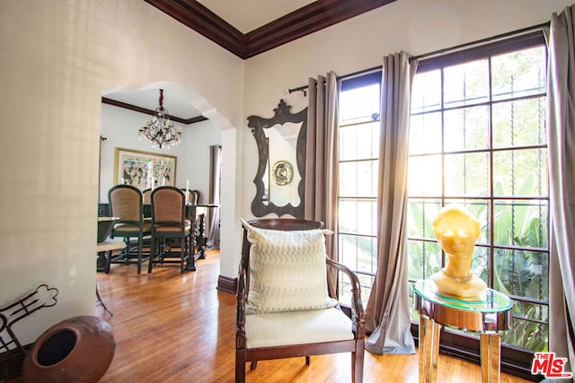 living area featuring crown molding, wood-type flooring, and an inviting chandelier