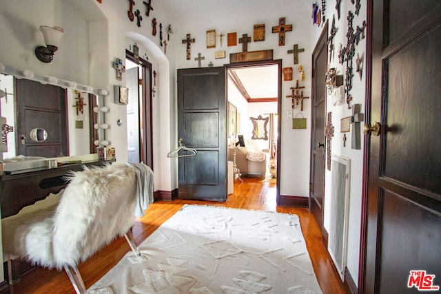 bedroom featuring ornamental molding, ensuite bathroom, and light hardwood / wood-style flooring