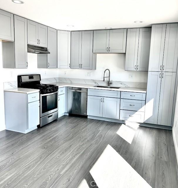 kitchen featuring appliances with stainless steel finishes, sink, gray cabinetry, and dark hardwood / wood-style floors