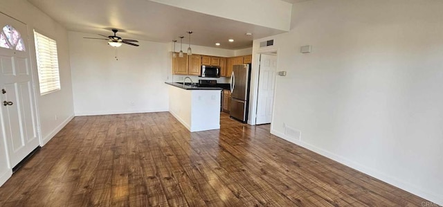 kitchen with appliances with stainless steel finishes, pendant lighting, ceiling fan, kitchen peninsula, and dark wood-type flooring