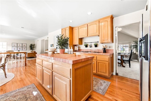 kitchen featuring tile counters, recessed lighting, light brown cabinetry, light wood-style floors, and a kitchen island